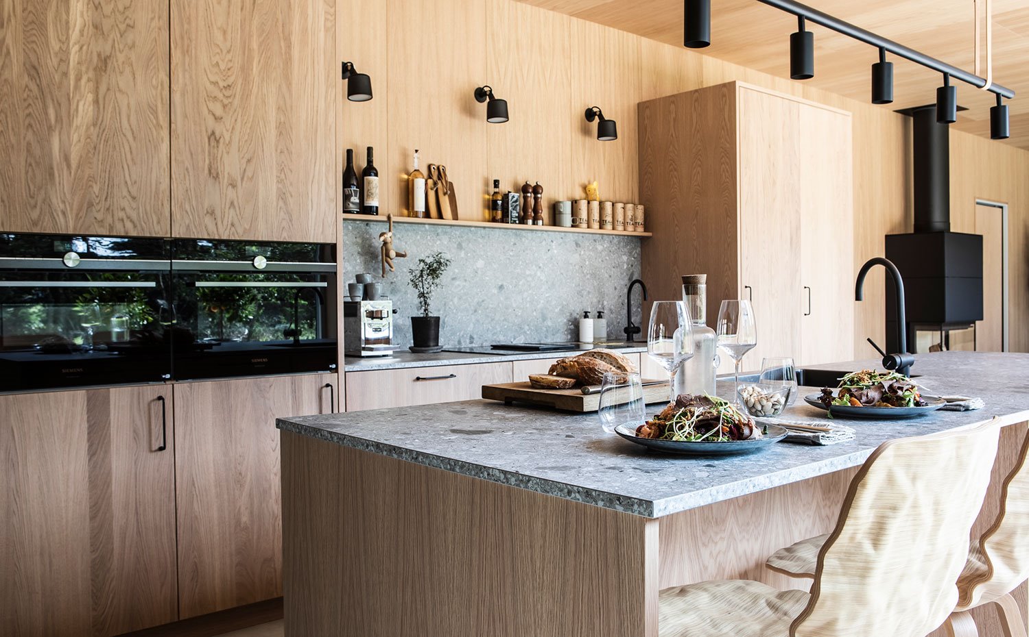 Isla central de la cocina con zona de office, dos taburetes de madera, encimera de granito.