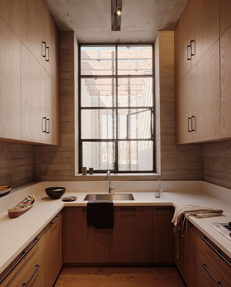 Cocina con disposición en forma de U, mobiliario con frentes de madera y encimera en crudo