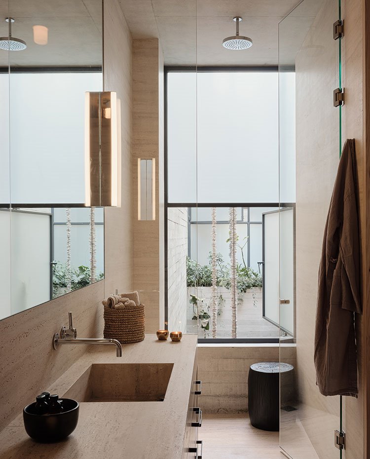 Cuarto de baño con zoja de tocador, puerta de cirstal y ducha asomando a apertura a patio en cristal translúcido