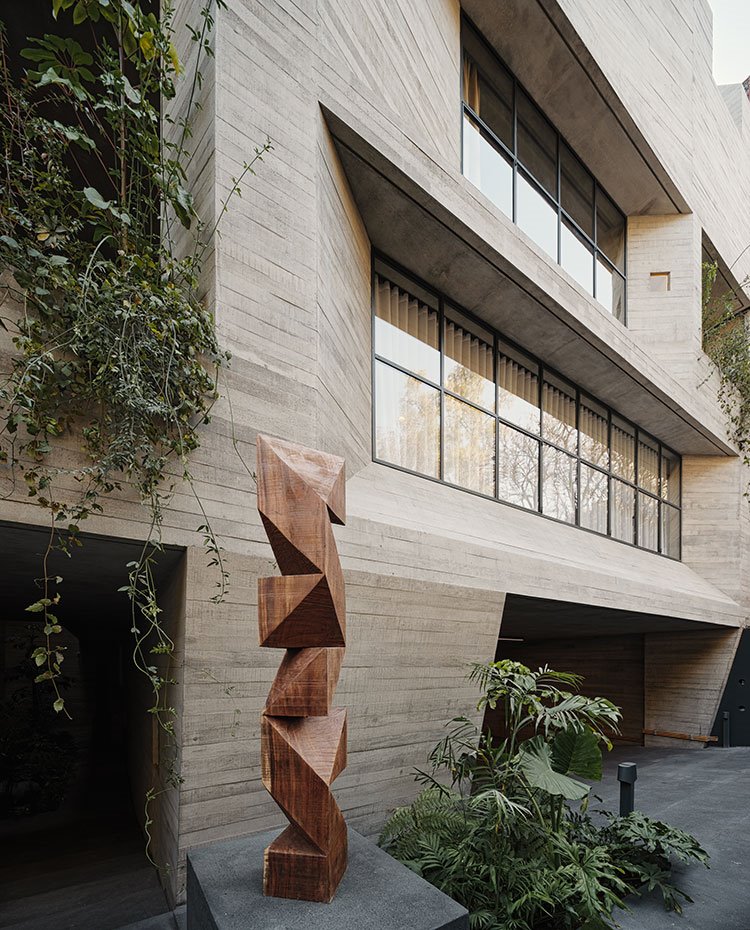 Escultura de madera en la entrada, junto a estructura irregular de la fachada