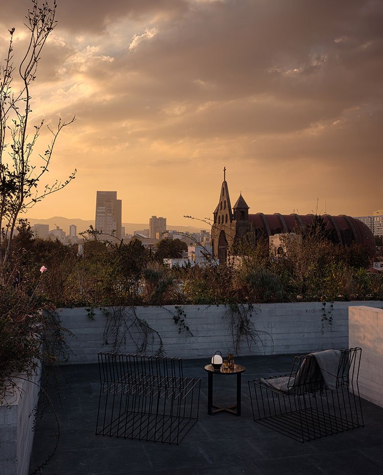 Terraza con butacas de rejilla y mesita auxiliar asomando al skyline de la ciudad