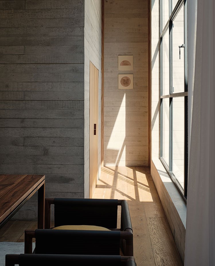 Rellano del apartamento con paredes de hormigón y suelo y puerta de madera, apertura lateral a exterior