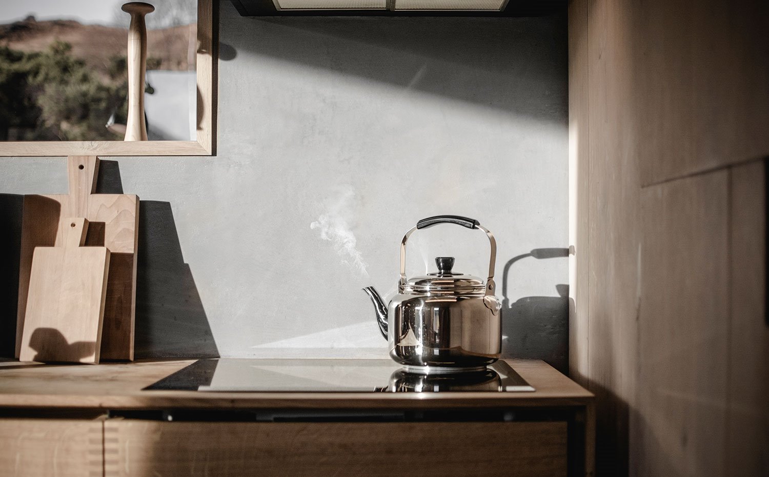 Placa de inducción en extremo de cocina con tetera, madera de cortar, ventana