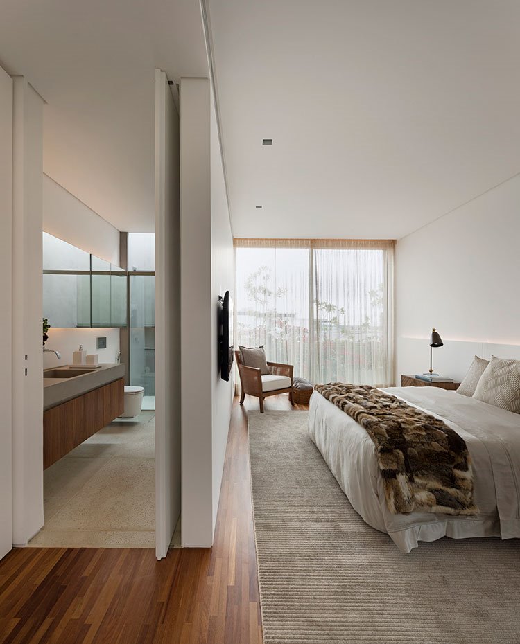 Dormitorio en suite, alfombra beige, suelo de madera, manta marrón sobre cama
