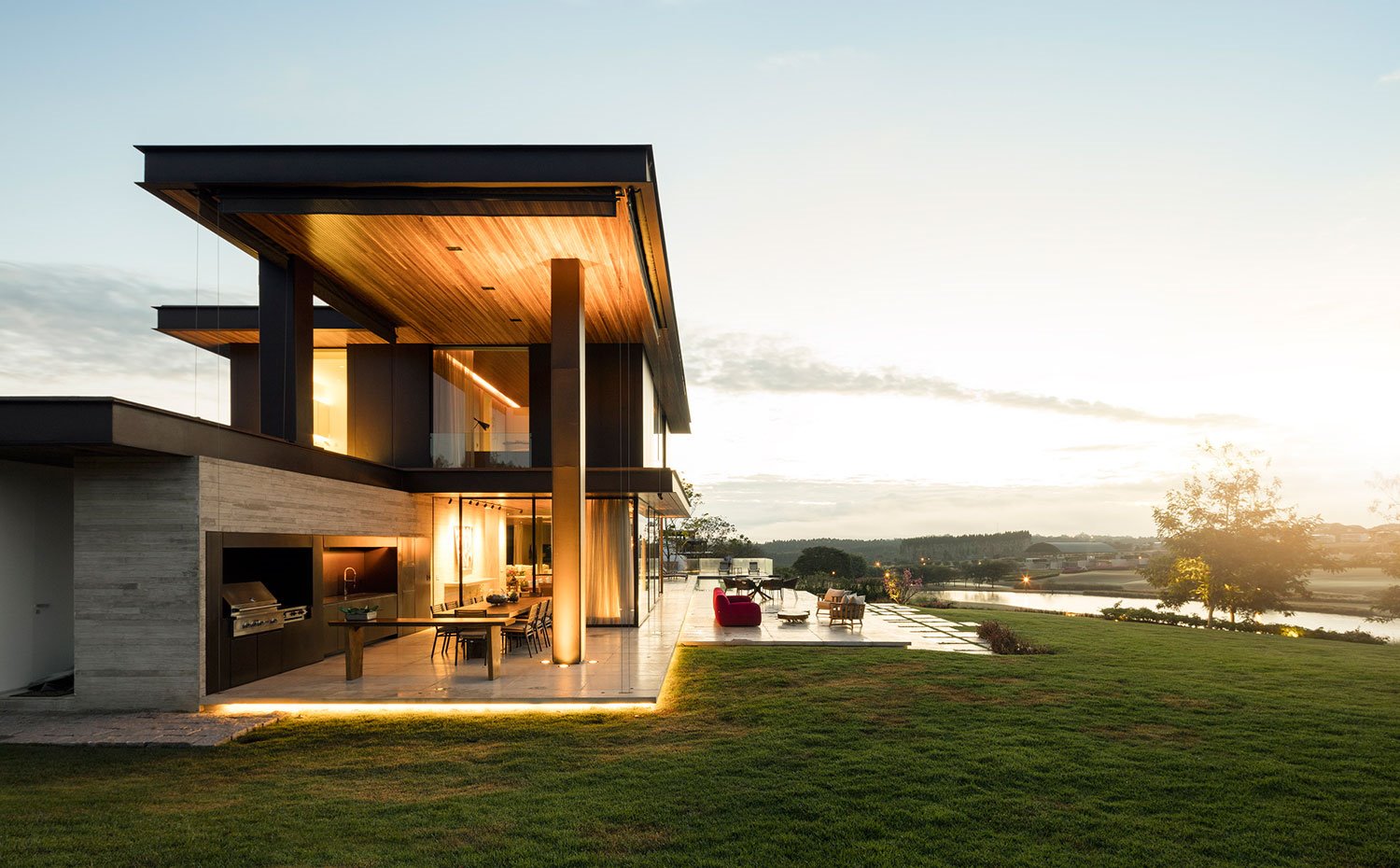 Estructura de la casa al anochecer, vista lateral con doble nivel y zona de barbacoa en un extremo de la terraza