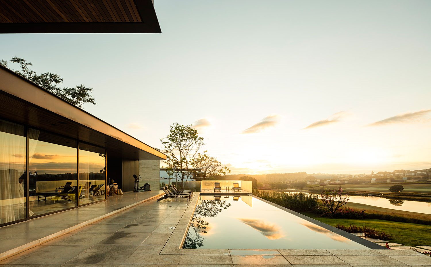 Piscina desbordante al amanecer, cerramientos acristalados, cubierta en voladizo