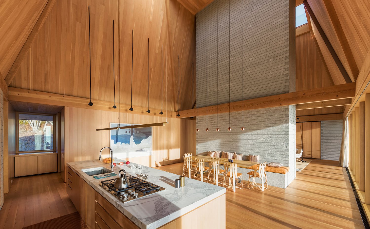 Cocina en isla con mobiliario de madera, encimera de mármol, revestimiento de madera