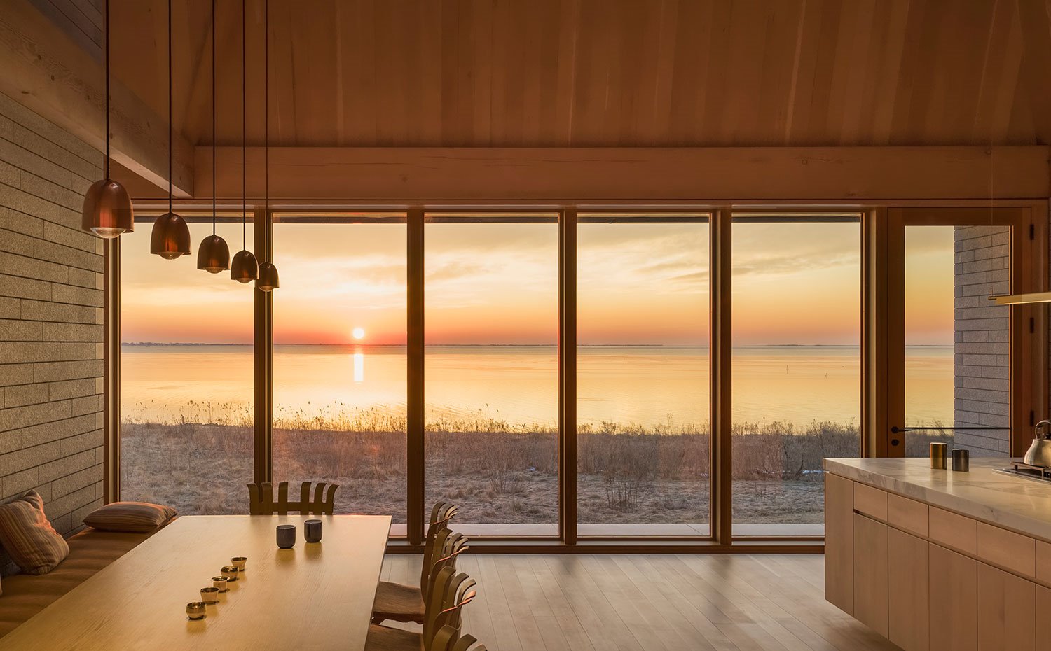 Comedor junto a cocina, con aperturas hacia paisaje exterior a lago