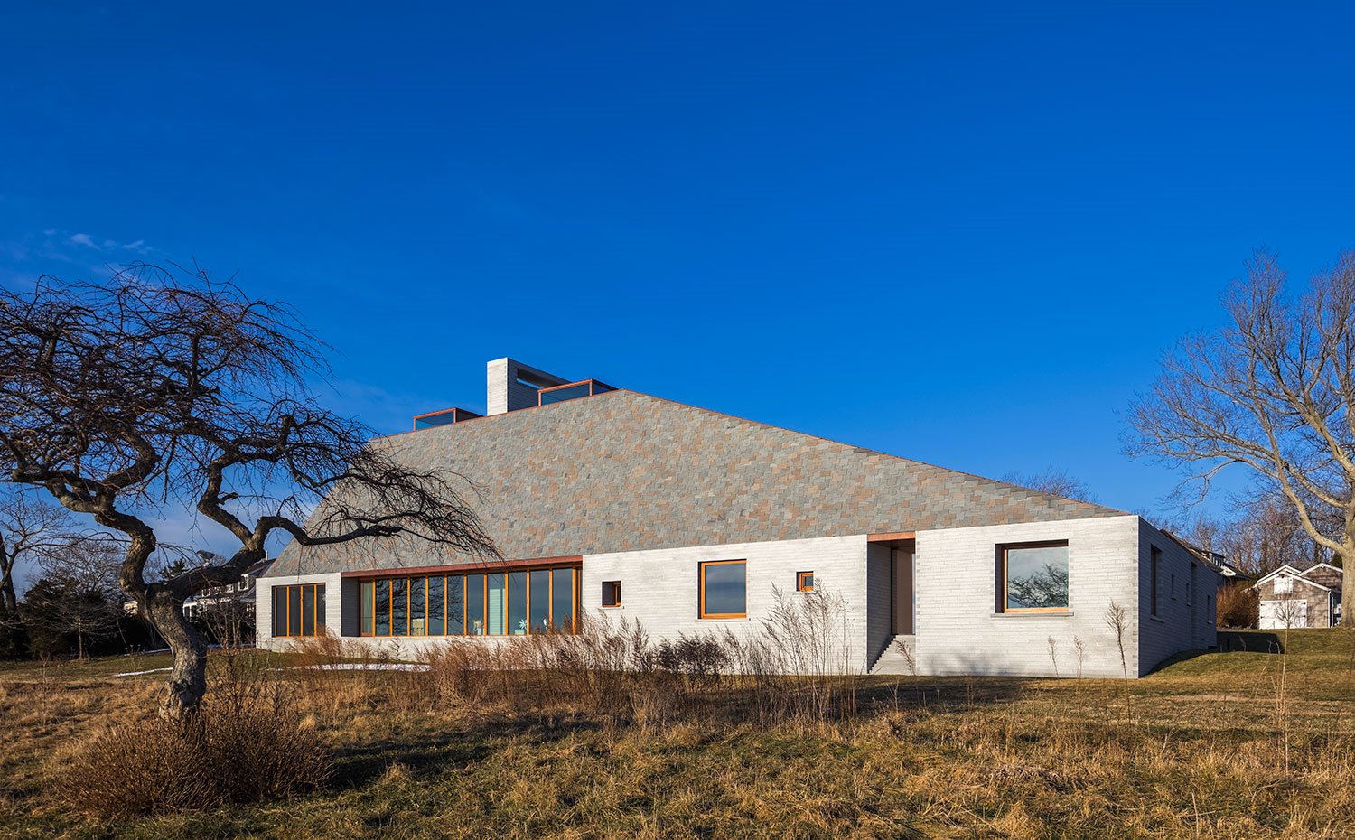 Fachada con varias aperturas hacia el exterior, piedra gris y cubierta en tonos grises y marrones