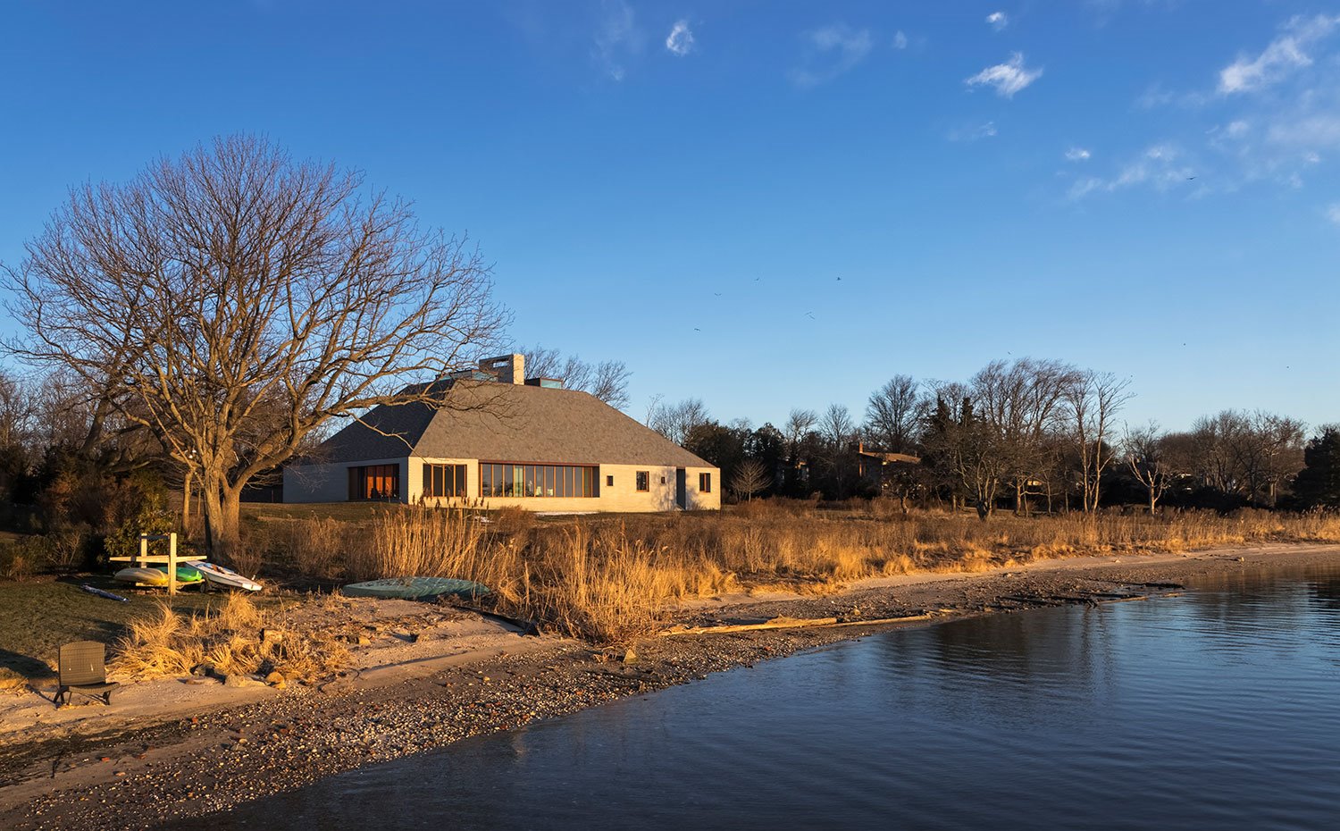 Vista exterior vivienda junto a lago con árboles y kayaks