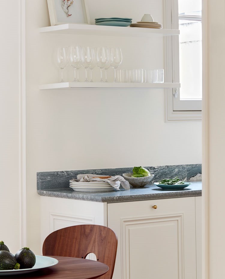 Cocina con mobiliario en blanco, baldas en la parte superior y encimera en gris