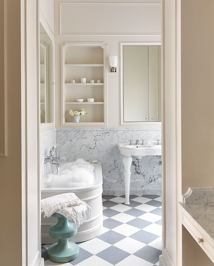 Cuarto de baño con suelo bicolor blanco y azul, hornacina en pared, perfilería de madera en blanco