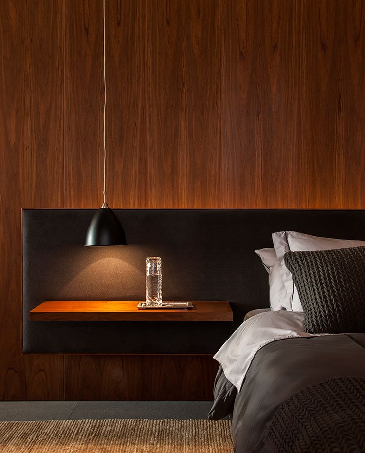 Detalle mesilla de noche de dormitorio a modo de balda de madera sobre cabecero  tapizado en negro