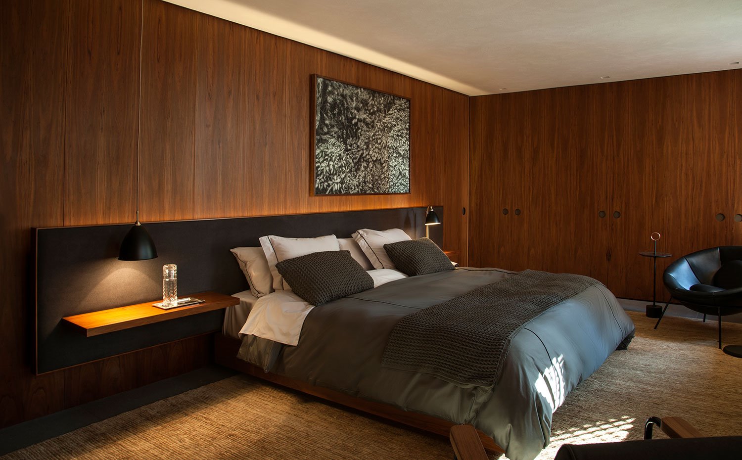 Dormitorio principal, paredes revestidas de madera, cabezal en gris con balda a modo de mesilla