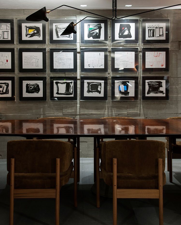 Mesa de comedor de madera, sillas de madera y tapicería marrón, serie de cuadros en pared