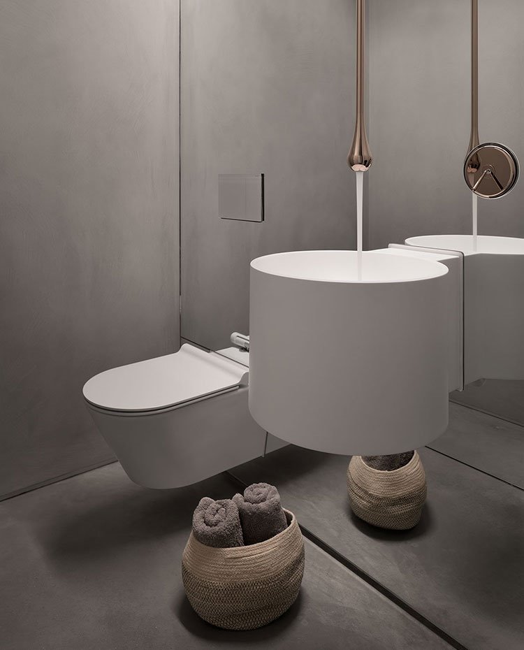 Cuarto de baño con revestimiento en cristal y acabado en gris. Equipamiento suspendido y grifería cromada y encastrada