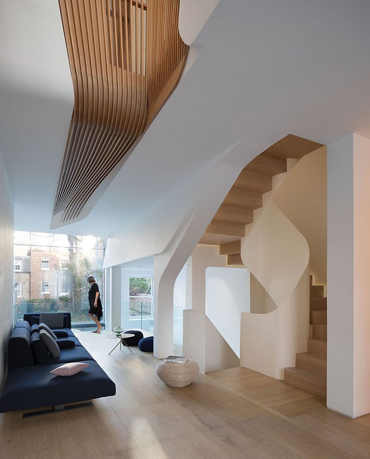 Salón con sofá en azul petróleo, estructura en blanco con suelo de madera, poufs en azul y cerramiento de cristal hacia exterior