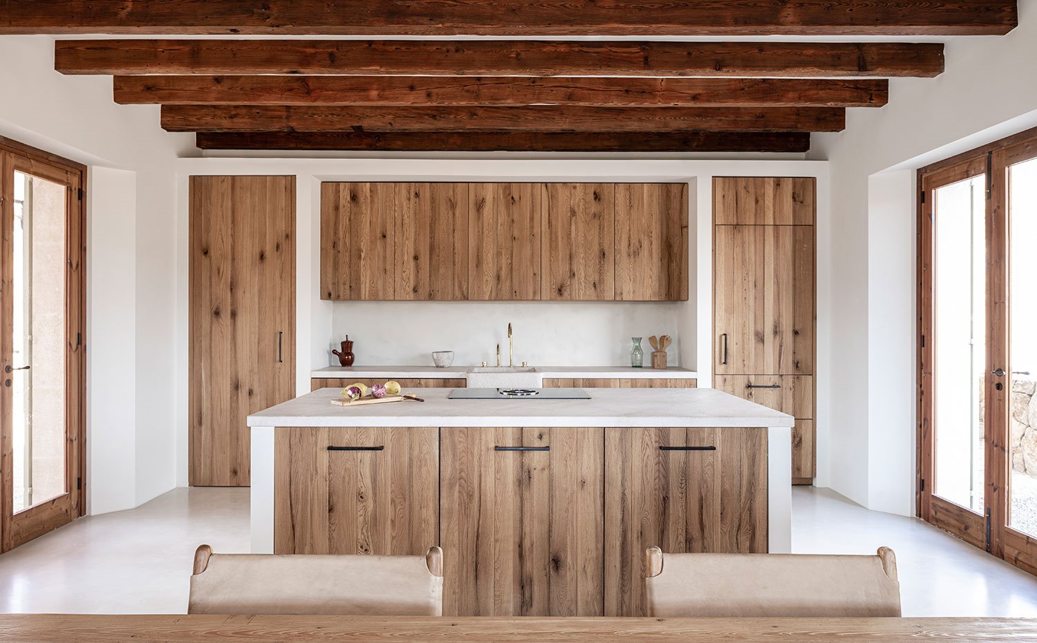 Cocina de madera hecha a medida, encimera en blanco, isla de trabajo, vigas en techo
