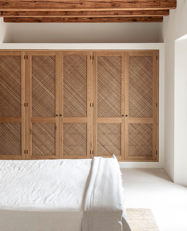 Dormitorio con armarios integrados en estructura con cerramientos de madera a modo de celosía, vigas en techo