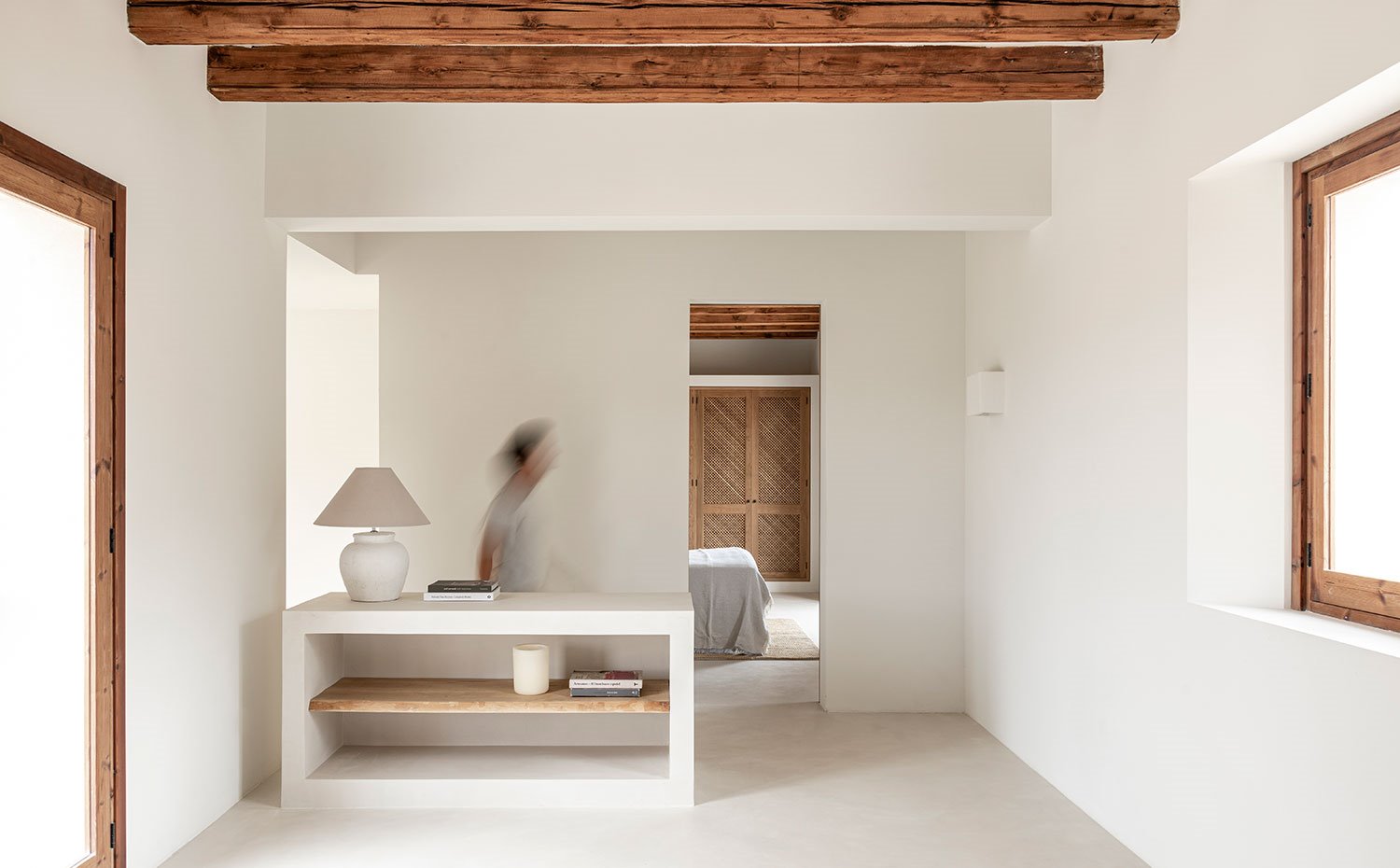 Mueble de obra en zona de paso a dormitorios, luminaria de sobremesa con pantalla de tela, balda de madera, vigas en techo