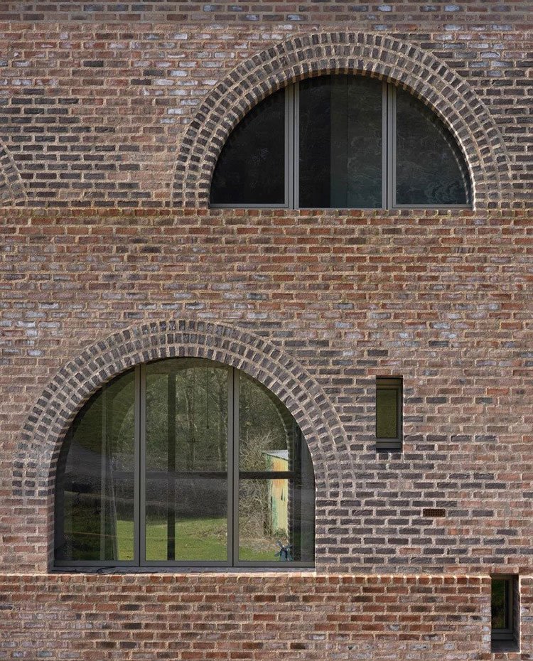 Fachada exterior con ladrillo visto y ventanas de medialuna