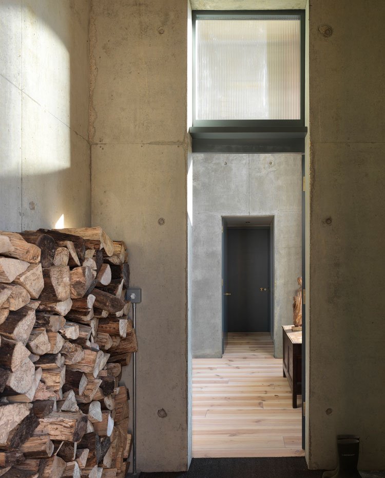 Zona de almacenaje de troncos de leña, abierto, con paredes en hormigón y pavimento de madera