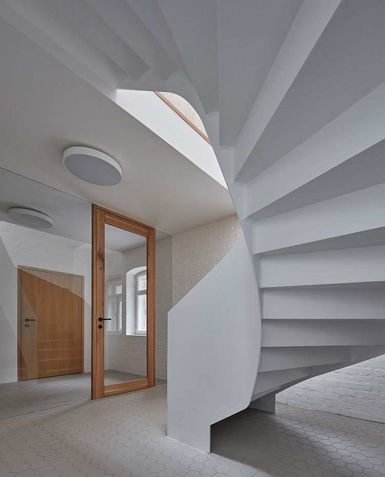 Interior de vivienda en blanco con carpintería en madera natural, plafones en el techo y escalera de caracol