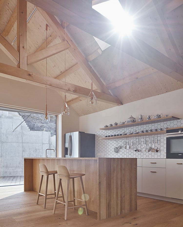 Isla de trabajo y taburetes de madera, vigas y techo de madera, mobiliario de cocina en blanco