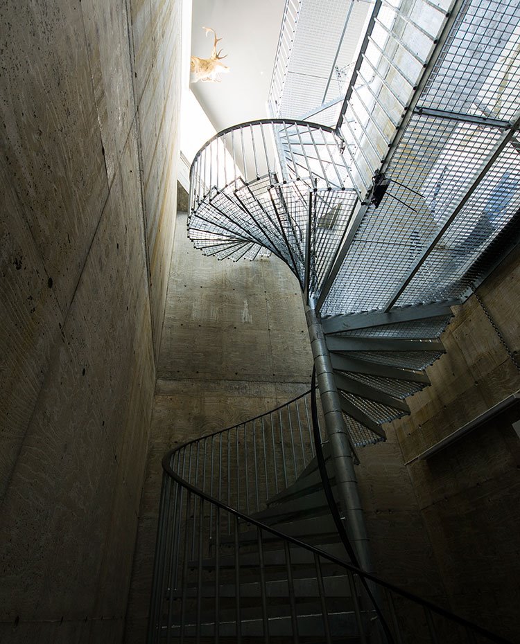 Estructura metálica con escaleras de caracol que descienden salvando el desnivel de la vivienda