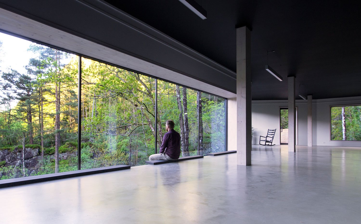 Interior de la vivienda diáfano, con columnas de hormigón, suelo pulido y cerramiento acristalado hacia exterior