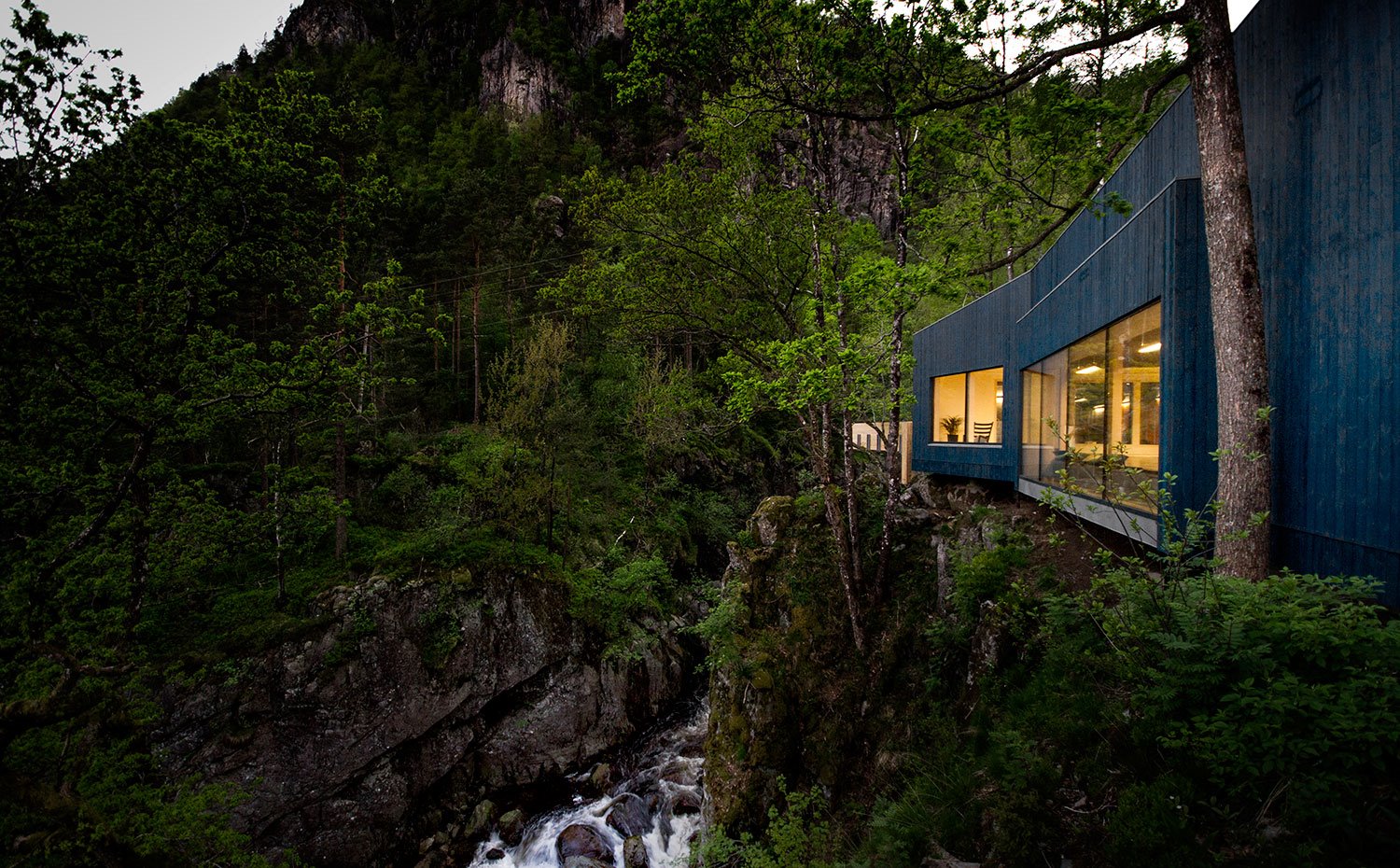 Paisaje natural con casacada y fachada con aperturas acristaladas