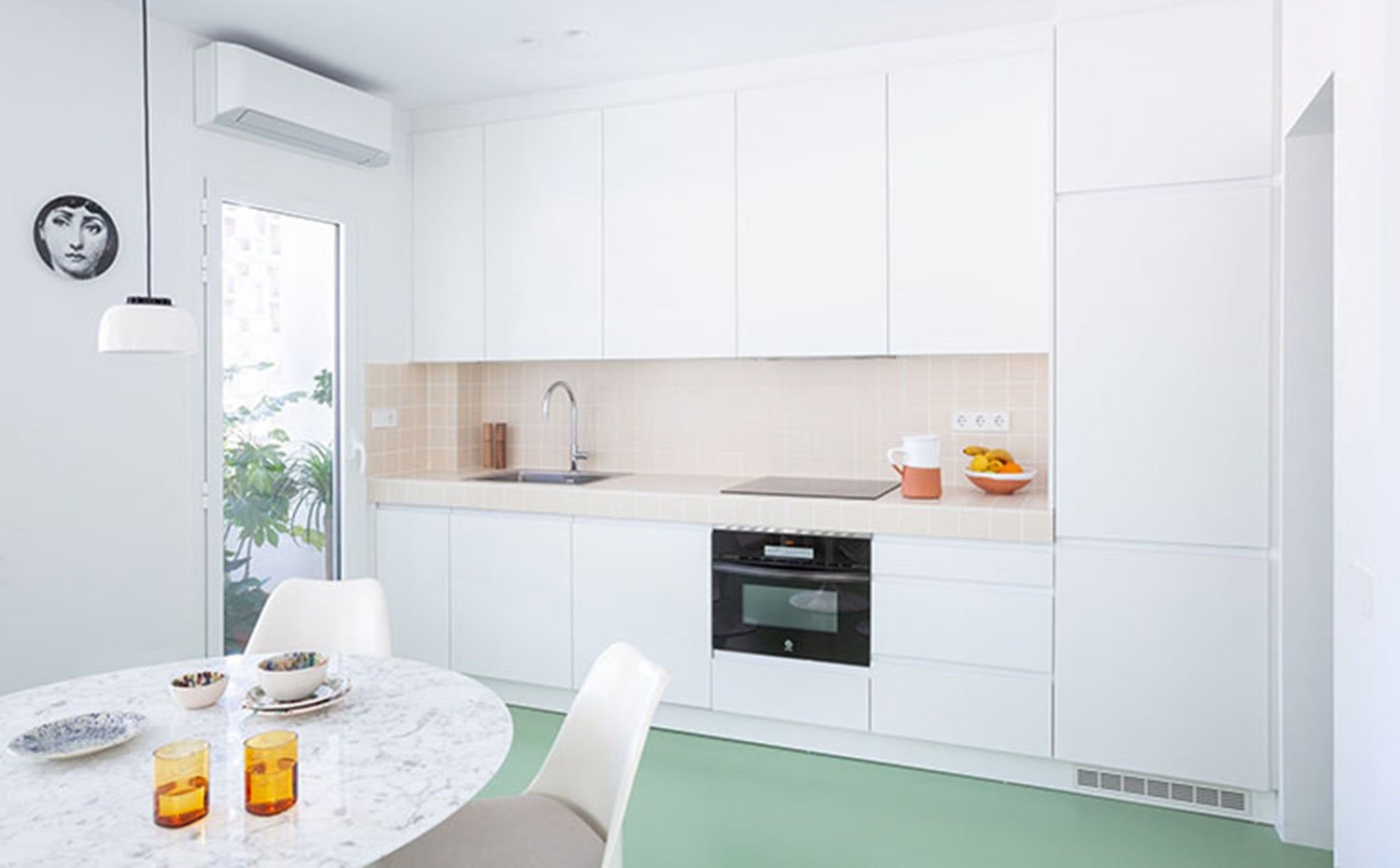 Cocina abierta con mobiliario en blanco junto a comedor