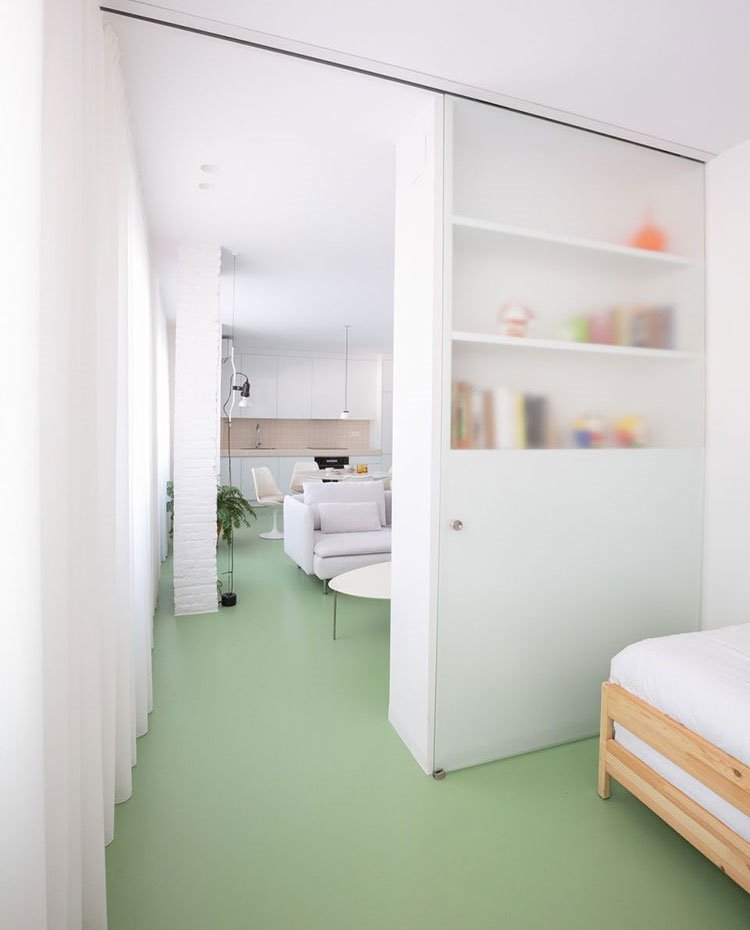 Dormitorio con suelo continuo verde, puerta corredera en cristal traslúcido
