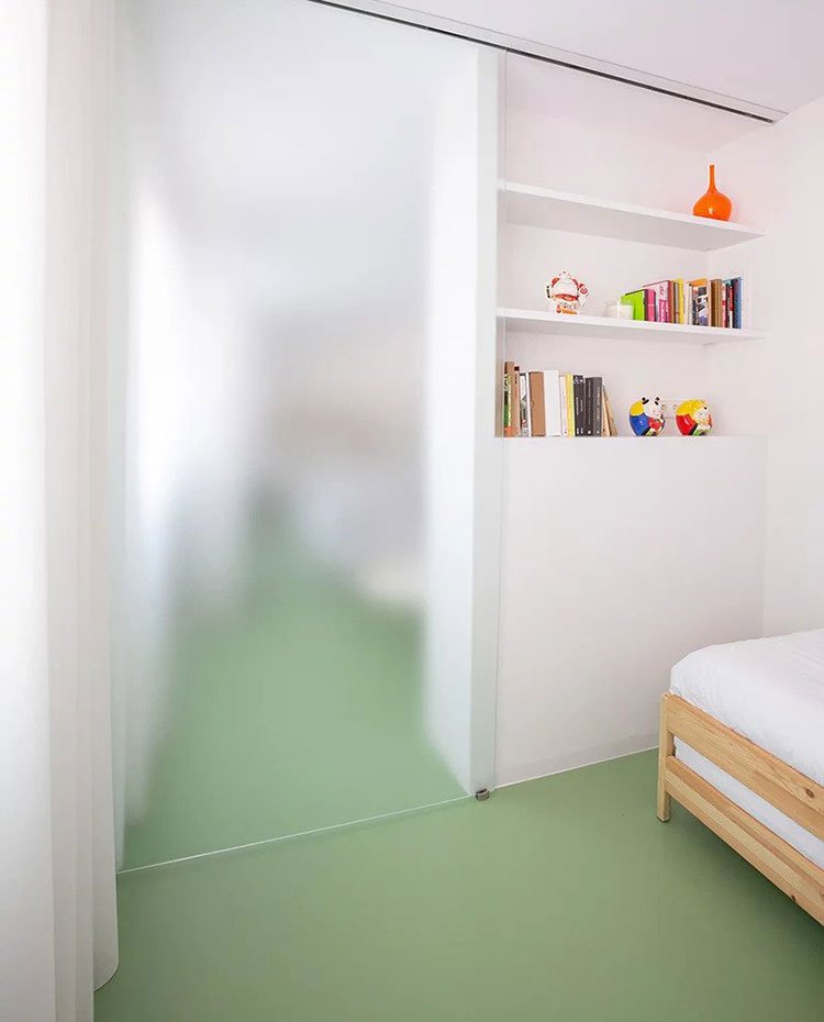 Puerta corredera de dormitorio infantil que se abre actuando como cerramiento de librería en pared