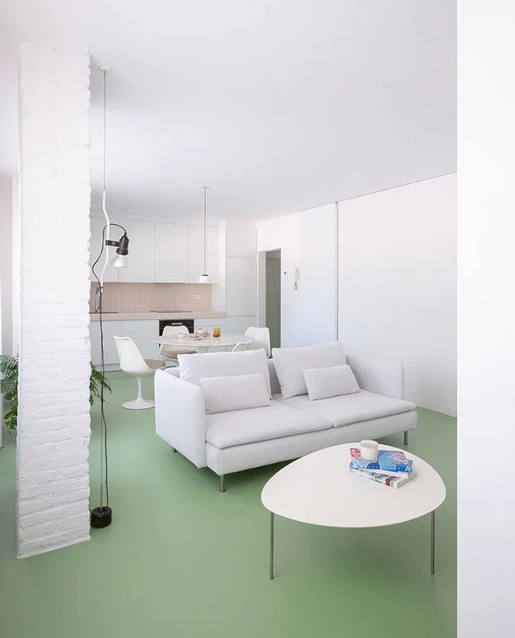 Zona de salón, comedro y cocina, todo en blanco con suelo en verde