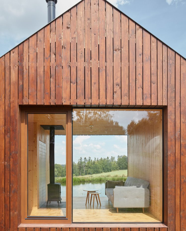 Apertura en fachada con vista interior a zona de estar con chimenea y vistas al lado del estanco