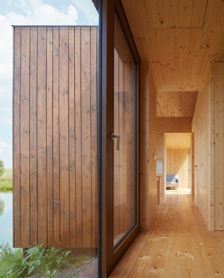 Cerramientos de cristal transparente y perfilería de aluminio junto a estructura revestida de madera
