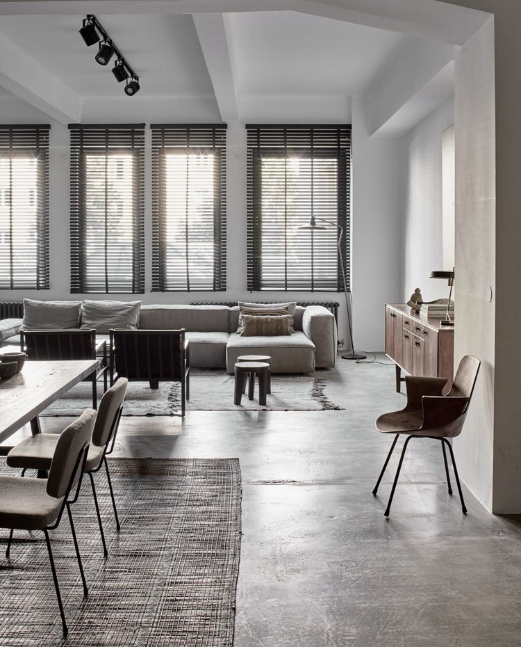 Comedor y salón con alfombras de lino deliminando las áreas, sillas y sofá en tonos crudos y butacas y muebles de madera