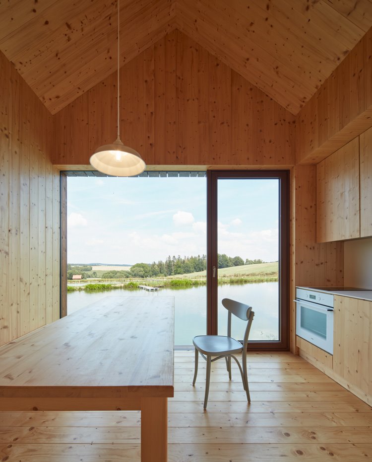 Mesa de cocina rectaungular de madera, techo a dos aguas todo revestido de madera, luminaria suspendida