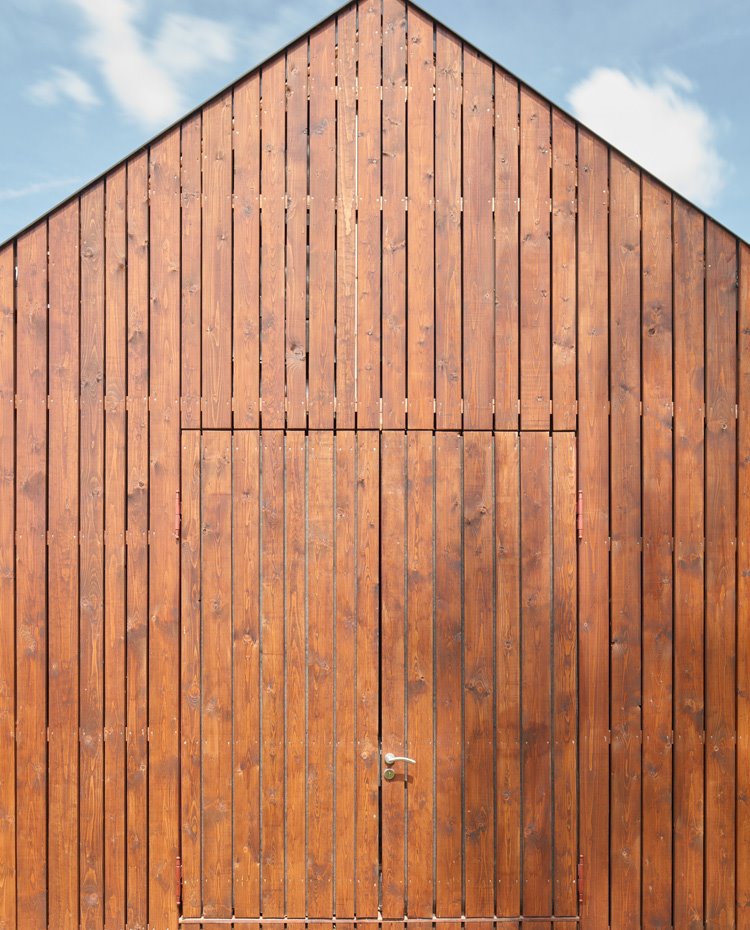 Puerta de entrada a la cabaña totalmente integrada a la fachada de madera alistonada