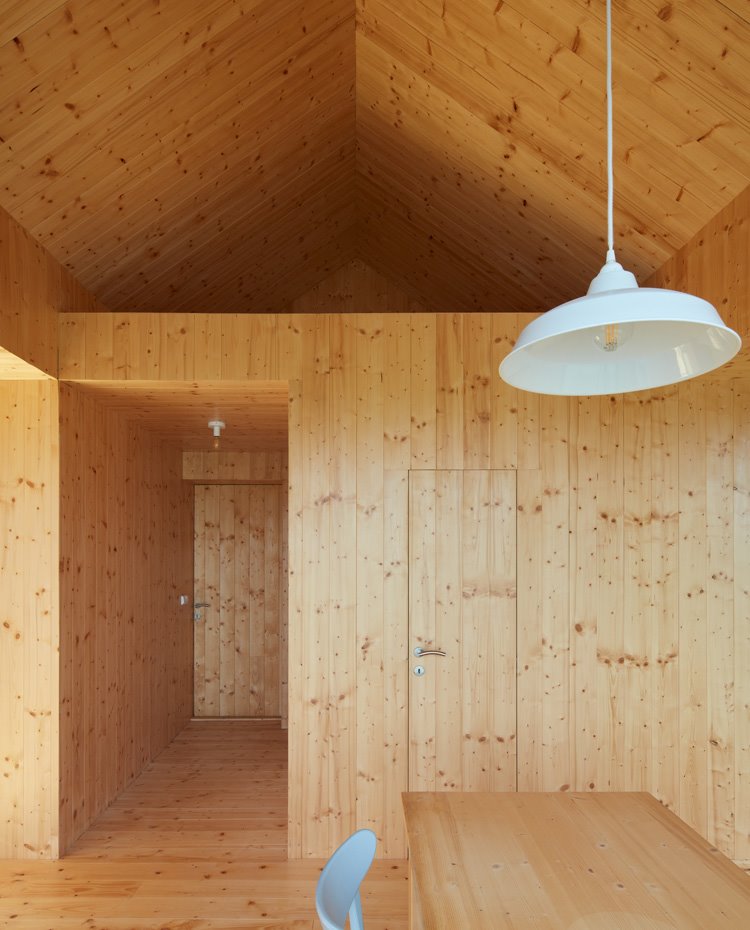 Puertas integradas en estructura de madera natural, luminaria suspendida blanca, silla ne gris