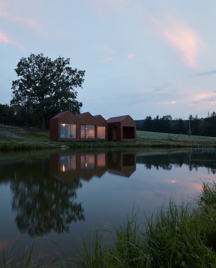 Vista nocturna de las cabañas co la iluminación interior y estructura reflejada en el agua