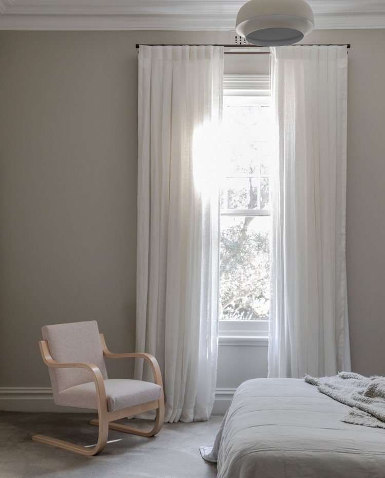 Dormitorio con butaca de estilo escandinavo, cortinas blancas y paredes en tonos pastel