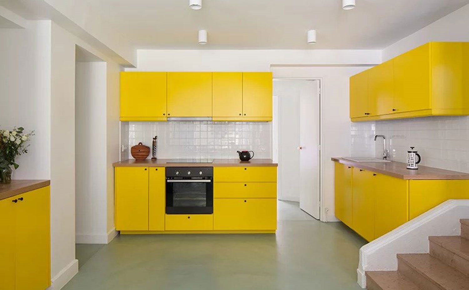 Cocina con mobiliario en amarillo y salpicadero con baldosas cuadradas en blanco