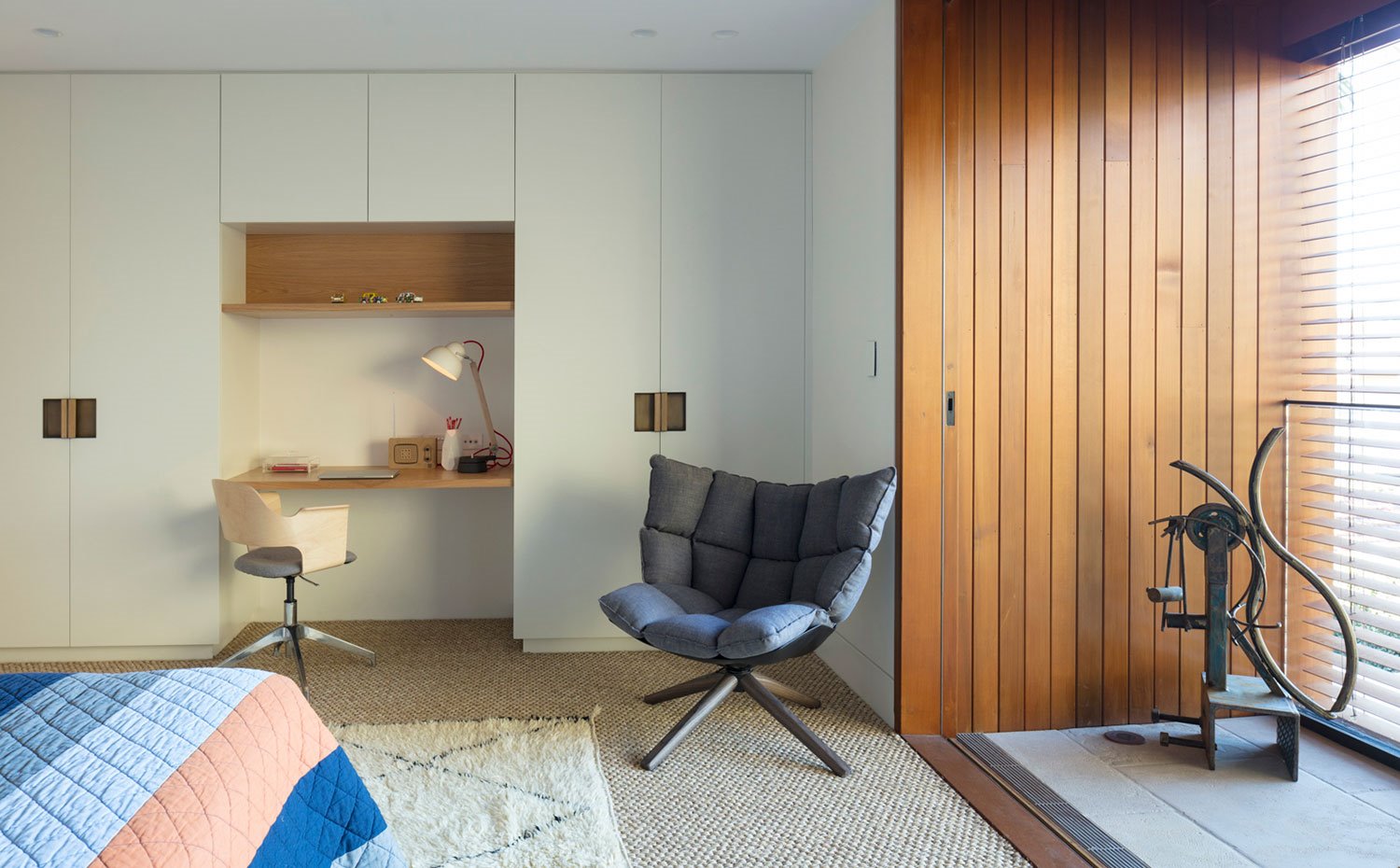 Dormitorio con zona de escritorio, butaca y rincón abierto revestido de madera
