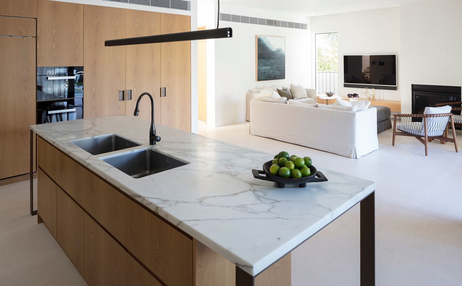 Isla de cocina y zona de almacenaje con salón al fondo