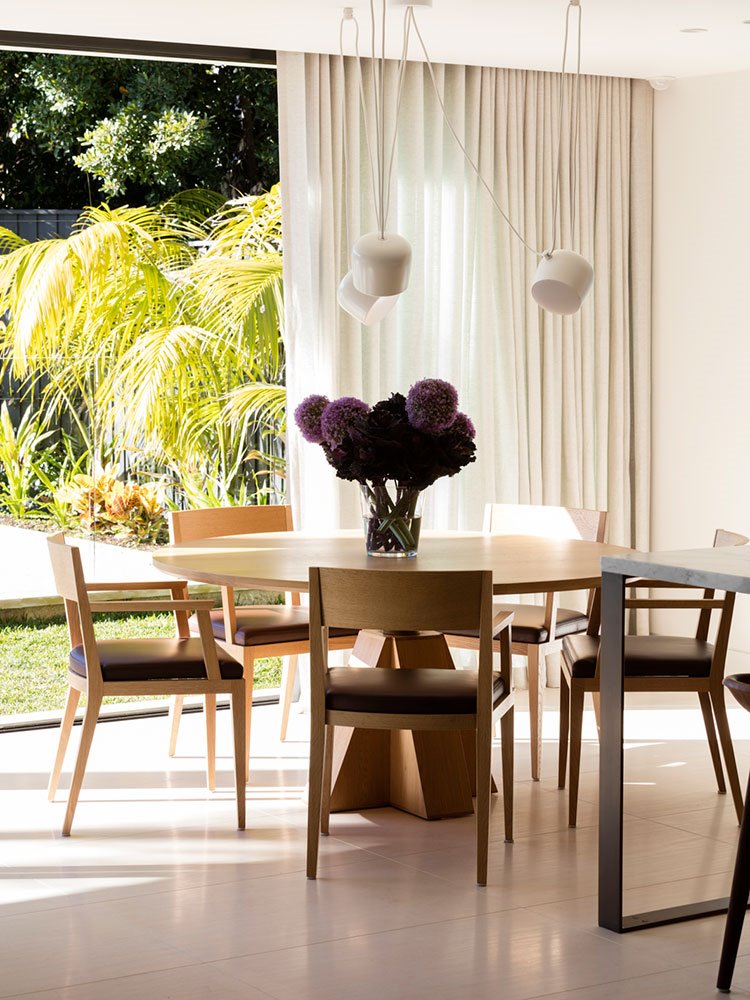 Mesa de comedor y sillas de madera orientadas junto a zona ajardinada exterior