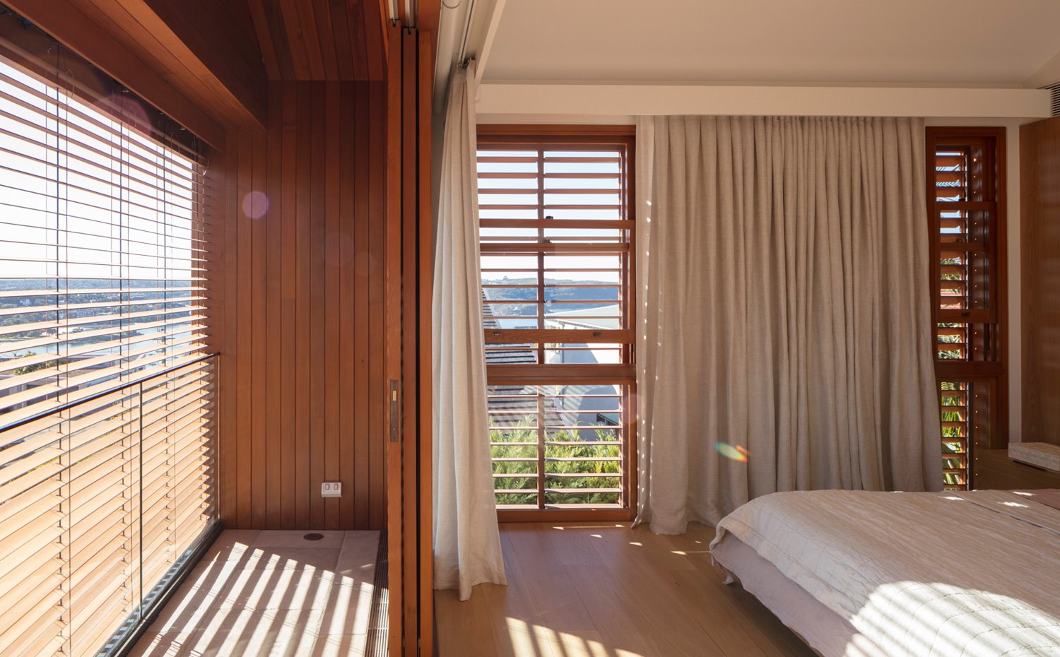 Dormitorio principal con vistas al océano a través de estores venecianos