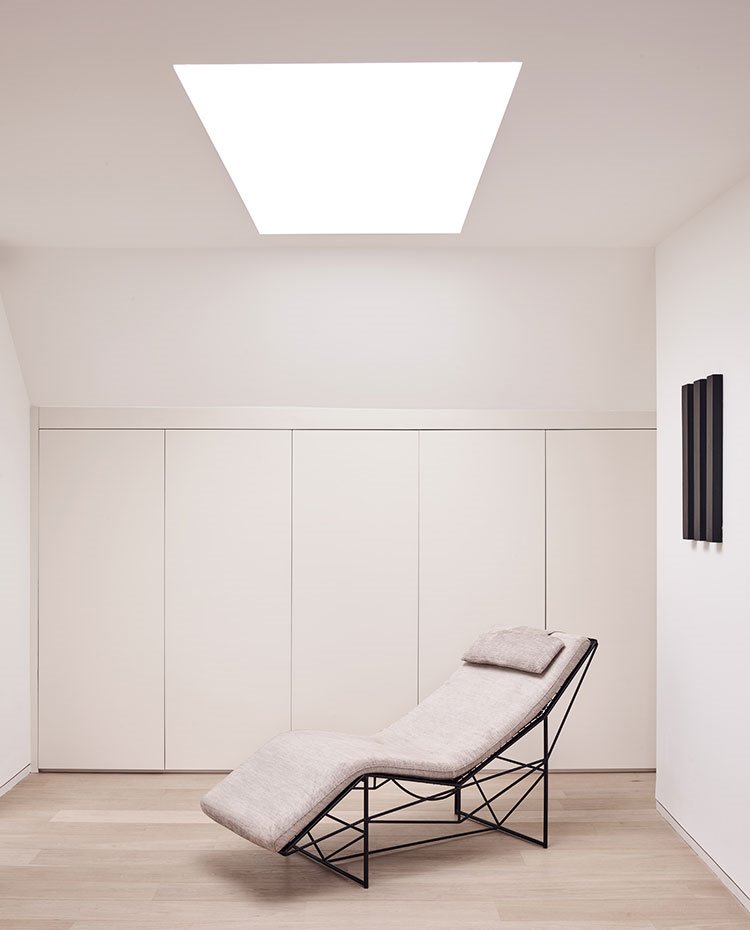Chaise-longue en crudo frente a armarios a medida y lucernario en el techo