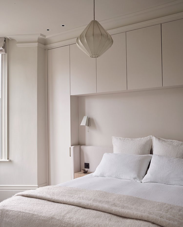 Dormitorio con mobiliario a medida alrededor de cabecero, luminaria suspendida y aplique blanco